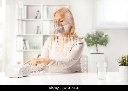 Frau, die zu Hause einen Vernebler anschaltet, medizinisches Behandlungskonzept Stockfoto