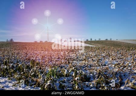 5G-Funkrelaisantenne auf einem schneebedeckten Feld im Kraichgau. Die Strahlung wird durch transparente Objekte symbolisiert. Stockfoto