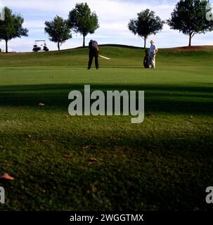 Ein Golfer und sein Caddy auf einem Golfplatz im Licht des späten Nachmittags. Stockfoto