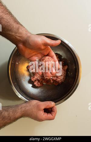 Mann formt Fleischbällchen in einer Metallschale Stockfoto