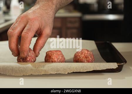 Ein Mann, der Fleischbällchen auf einen Blech legt Stockfoto