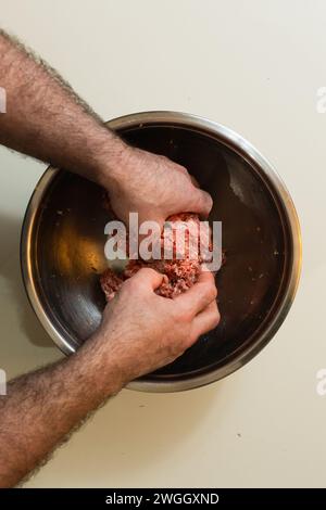 Mann, der Hackfleisch in einer Metallschale mischt Stockfoto