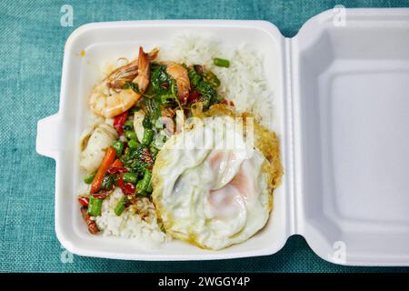 Gebratene Meeresfrüchte und Spiegelei mit heiligem Basilikum in Schaumstoffbox Stockfoto