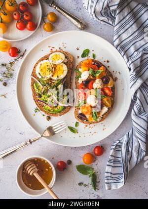 Teller Toast mit Avocado, Ei, Tomaten, Mozzarella. Stockfoto