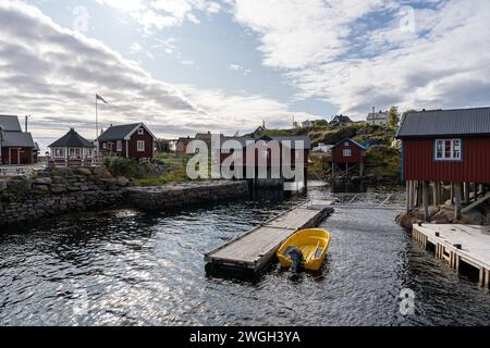 Ein lebhaftes, gelbes Boot liegt an einem Pier in einer malerischen Flusslandschaft, umgeben von bezaubernden Häusern Stockfoto