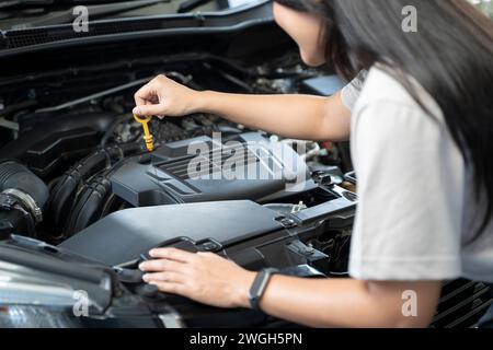 Frau, die neben einem Auto steht und den Motor überprüft. Stockfoto