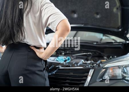 Asiatische Frau, die Probleme mit ihrem Auto hat schöne Frau, die kaputte Autos inspiziert, bevor sie zu Hause geht. Stockfoto