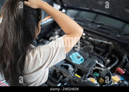 Asiatische Frau, die Probleme mit ihrem Auto hat schöne Frau, die kaputte Autos inspiziert, bevor sie zu Hause geht. Stockfoto