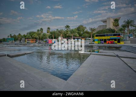 Skyline von Doha in West Bay Area Nachmittagsaufnahme vom Hotelpark mit künstlichem See im Vordergrund, Doha Hop-on Hop-off Bus und Sheraton Hotel Stockfoto