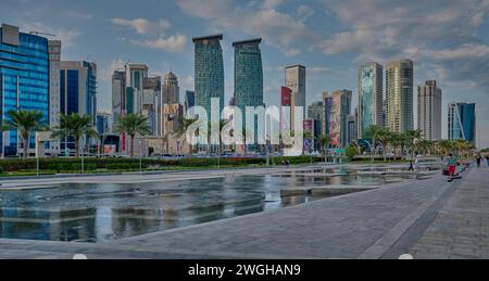 Skyline von Doha in der westlichen Bucht Doha, Katar Nachmittagsaufnahme aus dem Hotelpark mit künstlichem See im Vordergrund und Wolken im Himmel im Hintergrund Stockfoto