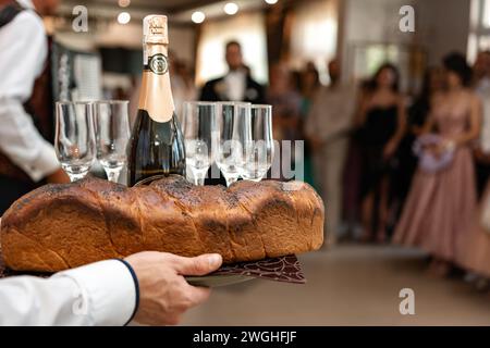 Traditionelles Hochzeitskalach bei einer Hochzeit in der Ukraine, Bräute und Hochzeitszeremonien. Der Kellner serviert Champagner mit Gläsern. Stockfoto