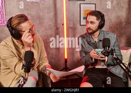 Gut aussehender Interviewer in lässiger Kleidung, der Fragen mit seinem jungen Gast während des Podcasts diskutiert Stockfoto