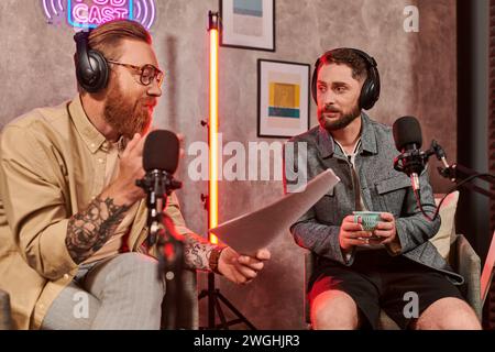 Gut aussehender Interviewer in lässiger Kleidung, der Fragen mit seinem jungen Gast während des Podcasts diskutiert Stockfoto