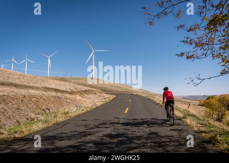 Mann fährt auf der Straße mit Windrädern im Hintergrund. Stockfoto