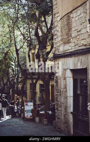 Enge Straße mit einer kleinen Terrasse im historischen Zentrum von Girona in Katalonien, Spanien, am 9. Dezember 2023 Stockfoto