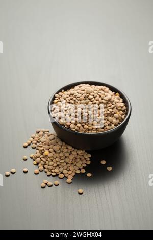 Braune Linsen in einer schwarzen Schüssel auf einem Holztisch. Stockfoto