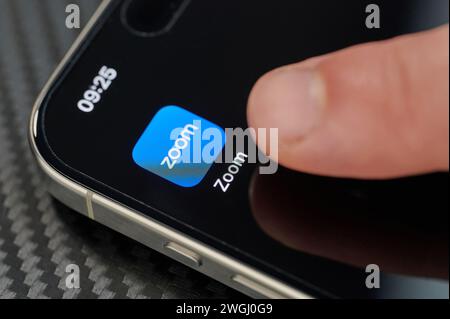 New York, USA – 24. Januar 2024: Berühren des oberen Symbols der geöffneten Zoom-App mit dem Finger auf dem iphone 15 Pro max. Nahaufnahme Stockfoto