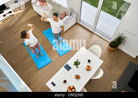 Glückliches Paar mittleren Alters, das nach dem Workout zu Hause High 5 gibt. Draufsicht Stockfoto