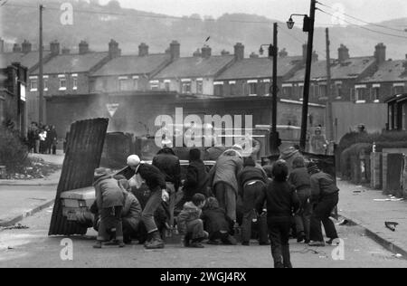 The Troubles Belfast Nordirland 1981. Ein entführtes Auto, das von jungen IRA-Jugendlichen in Brand gesetzt wurde und im Hintergrund als Barrikade im Benzinbombenkampf gegen die britische Armee eingesetzt wurde. 1980er Jahre Etna Drive, Ardoyne North Belfast UK 1980s HOMER SYKES Stockfoto