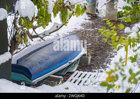 Landschaft mit schneebedeckten Bäumen, wunderschöner gefrorener Fluss. Ein Boot, das mit Schnee bedeckt ist. Stockfoto