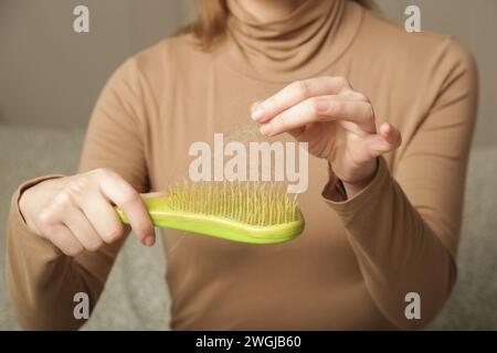 Eine Frau, die eine Haarbürste mit Haarausfall hält. Haarausfall Stockfoto