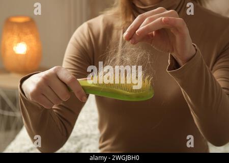 Eine Frau, die eine Haarbürste mit Haarausfall hält. Haarausfall Stockfoto