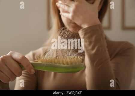 Eine Frau, die eine Haarbürste mit Haarausfall hält. Haarausfall Stockfoto