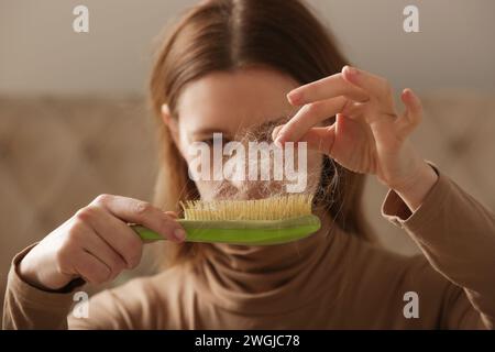 Eine Frau, die eine Haarbürste mit Haarausfall hält. Haarausfall Stockfoto