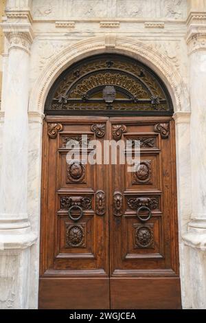 Schöne geschnitzte Holztür über die Marmorwand in Nahaufnahme. Außenfassade des Gebäudes Stockfoto