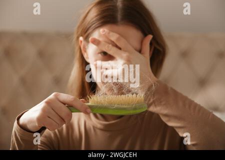 Eine Frau, die eine Haarbürste mit Haarausfall hält. Haarausfall Stockfoto