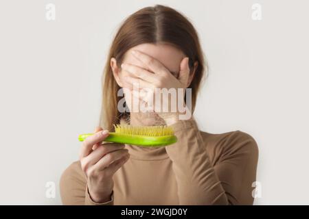 Eine Frau, die eine Haarbürste mit Haarausfall hält. Haarausfall Stockfoto