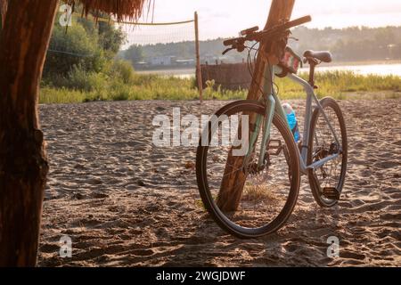 Rennrad an einem Sandstrand am Fluss bei Sonnenaufgang. Aktives und sportliches Morgenkonzept. Stockfoto