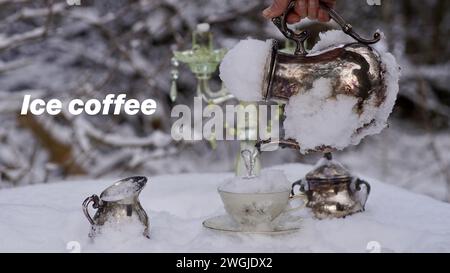 Eine Hand, die eine gefrorene silberne Kaffeekanne hält und Eis in eine Tasse gießt. Milch- und Zuckerkanne. Schnee. Stockfoto