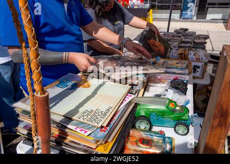 Zwei Leute suchen sich in Stapeln von Vinyl-33 1/3-Platten zum Verkauf an einem Straßenstand der Harlingen Market Days, Harlingen, Texas, USA. Stockfoto