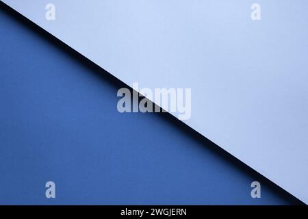 Abstrakter geometrischer Hintergrund zweier blauer Papierstücke, die mit einem Schatten übereinander liegen. Stockfoto