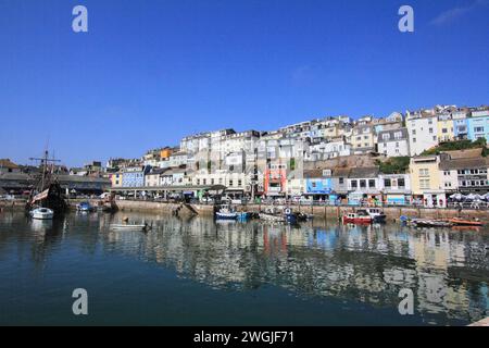 Brixham Hafen Torbay, South Devon mit Terrassen von bunten Geschäften und verschiedenen Stilen von Cottages/Häusern mit Blick auf den alten Fischmarkt auf dem Qua Stockfoto