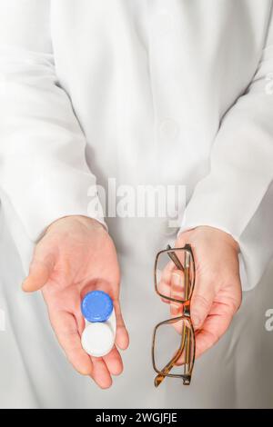 Hände einer Optikerin im weißen Mantel, die Brille und Kontaktlinsen in der Hand hält Stockfoto