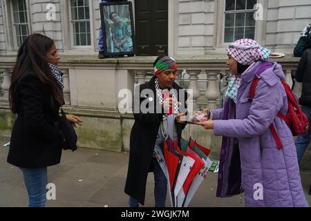 Eine Frau, die hans als Süßigkeiten ausgibt, als Hunderttausende marschieren, die einen Waffenstillstand in Gaza in Whitehall fordern. Stockfoto