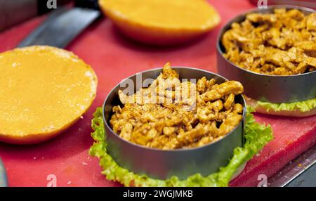 Ein Blick aus nächster Nähe auf einen köstlichen Mini-Burger-Vorspeise mit saftigem Fleisch, geschmolzenem Käse und frischen Toppings auf einem leuchtend roten Hintergrund Stockfoto