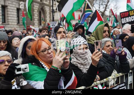 Demonstranten filmen auf ihren Telefonen als Hunderttausende pro-palästinensische Demonstranten, die eine Waffenruhe in Gaza-Stadt in Whitehall fordern. Stockfoto