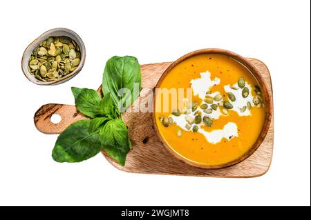 Kürbissuppe mit Sahne, Samen und frischem Basilikum in einer rustikalen Holzschale. Isoliert auf weißem Hintergrund. Draufsicht Stockfoto