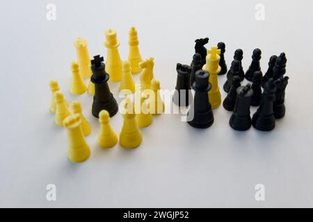 Schwarz-weiße Schachfiguren, die strategisch auf weißem Hintergrund angeordnet sind, symbolisieren Zusammenarbeit und Führung innerhalb eines Teams. Stockfoto