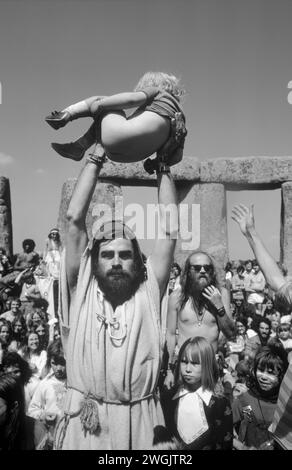 BEV Richardson ist auch bekannt als Pagan Bev hält einen kleinen Jungen, der gerade getauft wurde, damit die Menge feiern kann. Seine Schwester steht neben Bec. Stonehenge Free Festival bei der Sommersonnenwende, Wiltshire, England, Juni 21. 1979. 1970S GB HOMER SYKES Stockfoto