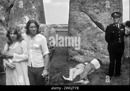 Stonehenge Free Festival bei der Sommersonnenwende, Wiltshire, England, Juni 21. 1979. Neben den Hippies beobachtete eine kleine Gruppe englischer Touristen, wie andere in der Sonne lagen, und ein 'Wachmann' stand daneben. 1970S GB HOMER SYKES Stockfoto