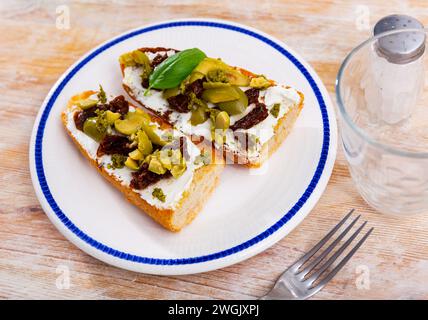 Getoastete Sandwiches mit Frischkäse, sonnengetrockneten Tomaten und Oliven Stockfoto