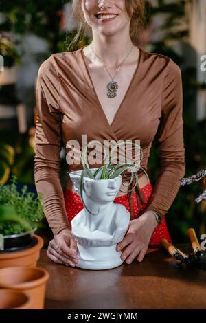 kaukasische Assistentin bei der Arbeit mit Sukkulenten ohne Boden im modernen Topf im Blumenladen. Stockfoto