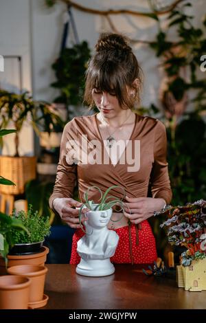 Vertikal-Schuss-kaukasische Assistentin, die mit Sukkulenten ohne Boden in einem modernen Topf im Blumenladen arbeitet. Stockfoto