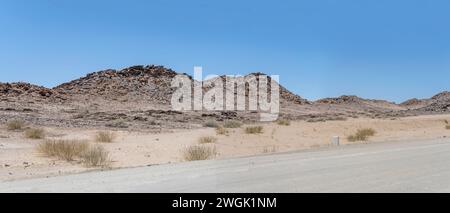Landschaft mit Doleritfelsen an der Seite der C37-Schotterstraße, aufgenommen im hellen Licht des späten Frühlings in der Wüste nördlich von AIS, Namibia, Afrika Stockfoto