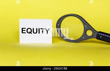 Das Wort EQUITY steht auf einem Aufkleber auf gelbem Hintergrund mit einer Lupe Stockfoto