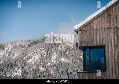 Moderne Holzhütte mit Fenster und Schnee auf dem Dach, Haus in der Niederen Tatra, Slowakei Stockfoto